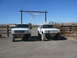 1988 Ford Bronco - Two modified Ford Broncos are parked in front of a ranch entrance under a steer skull decoration.