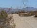 1988 Ford Bronco - A dirt road winds through a desert landscape with large power line towers in the distance.