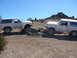 1988 Ford Bronco - Two white Ford Broncos are shown off-roading on a sunny day with rocky hills in the background.