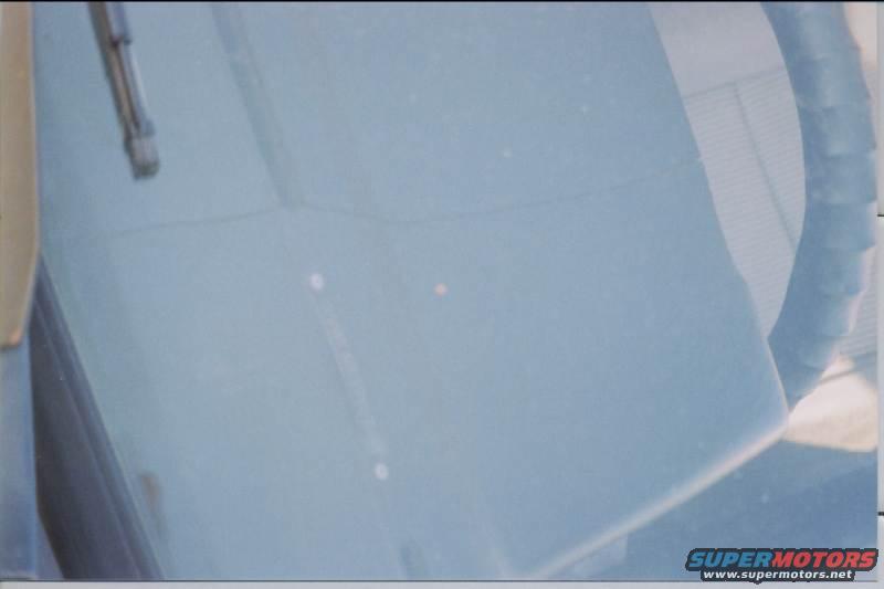 Light blue dashboard and windshield with wiper arm. Water spots visible on glass