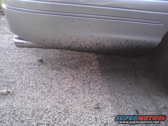 Silver car's rear bumper and exhaust pipe covered in mud splatters