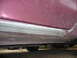1993 Mazda MX-3 - Close-up view of a car's side skirt with visible wear and tear.