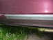 1993 Mazda MX-3 - Close-up view of a red car's side skirt, showing the silver trim and mounting hardware.