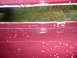 1993 Mazda MX-3 - Close-up of a red car part showing stamped text and white speckles.