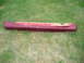 1993 Mazda MX-3 - A single red side skirt part is shown lying on a grassy surface.