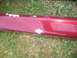 1993 Mazda MX-3 - This close-up shows a red car's side skirt with areas of chipped paint revealing the primer beneath.