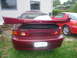 1993 Mazda MX-3 - Rear view of a maroon 1993 Mazda MX-3 with a prominent spoiler and dual exhaust pipes.