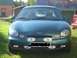 1996 Ford Taurus - A green 1996 Ford Taurus is parked in a grassy area with buildings in the background.