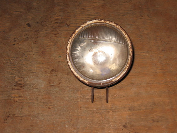 Round headlight with a rusty bezel and ribbed glass lens