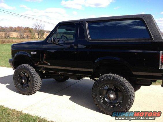 Black lifted Ford Bronco with aftermarket wheels, seen from the side