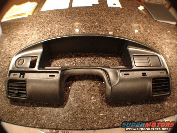 Black dashboard trim piece with air vents and control openings