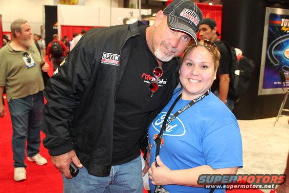 Man in a black jacket and cap poses with a woman wearing a blue Ford t-shirt