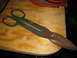2004 Aston Martin Virage - A pair of well-used Wiss tin snips with green handles and rusty blades rests on a wooden surface.