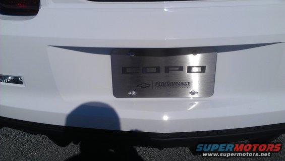 White car rear bumper with COPO Performance license plate frame. Supermotors.net logo visible