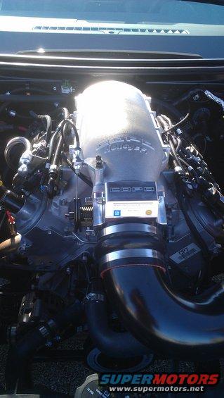 Close-up of a car engine with a large silver Holley intake manifold and black hoses