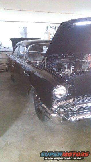 Black 1957 Chevrolet Bel Air sedan with hood open, showing engine and chrome front grille