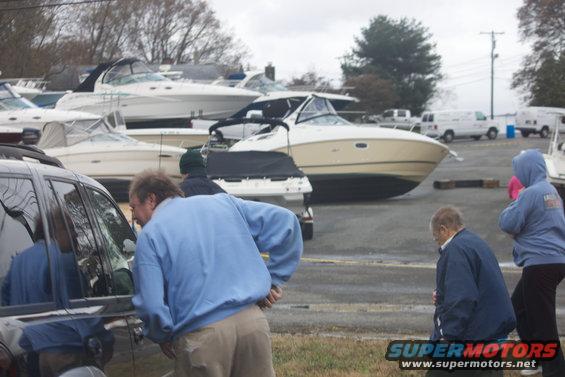 Several boats are parked on land, with people standing around them