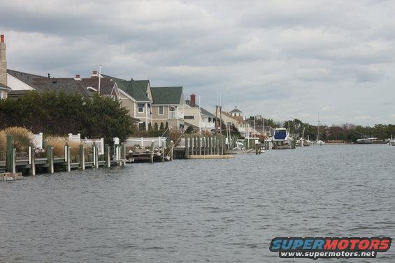 Waterway with houses and docks, a blue boat is visible in the distance
