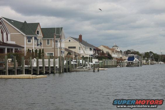 Blue and white boat on a trailer by a dock with houses