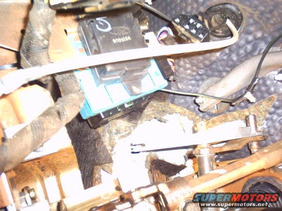 Close-up of automotive wiring and a blue electronic module under the dashboard