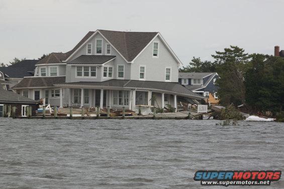 Flooded houses on a waterfront with debris scattered around