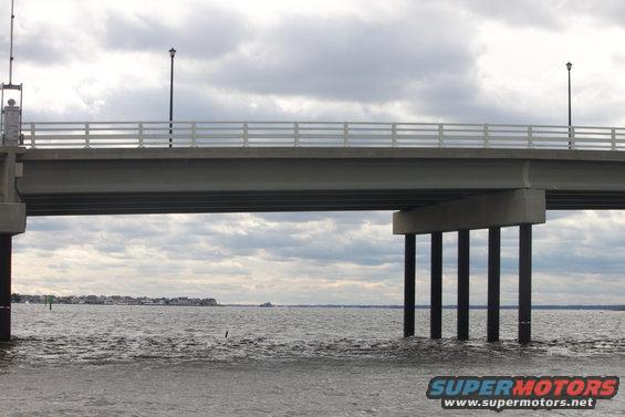 Bridge over water with cloudy sky and distant shoreline