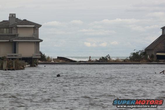 Flooded coastal area with houses on stilts and debris in the water