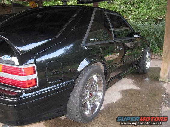 Black 1993 Ford Mustang coupe with chrome wheels, rear quarter view