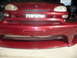 1993 Mazda MX-3 - The front bumper of a red 1993 Mazda MX-3 is shown, a mesh grille and license plate mounting area.