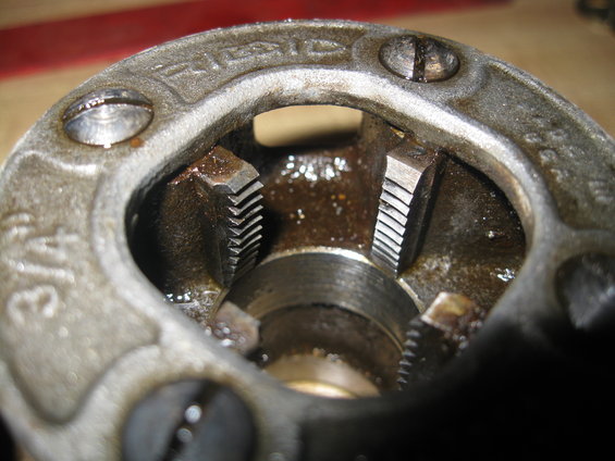 Pipe threading die with 3/4 marking and Ridgid logo, showing internal cutting teeth and oil