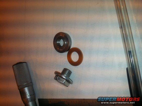 Transmission pan drain plug with washer, a metal cylinder, and a micrometer on a white surface
