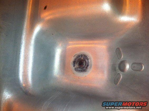 Close-up of a transmission pan drain plug with some residue around it. There's a three-pronged shape on the right