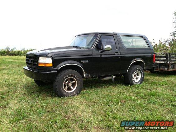 Black 1992 Ford Bronco parked on grass, towing a trailer
