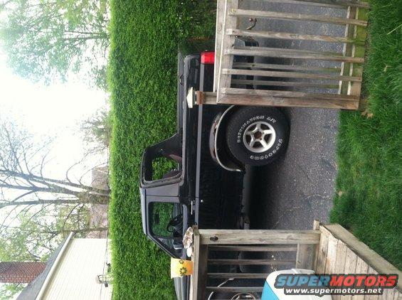 Black pickup truck parked next to a wooden deck and hedge