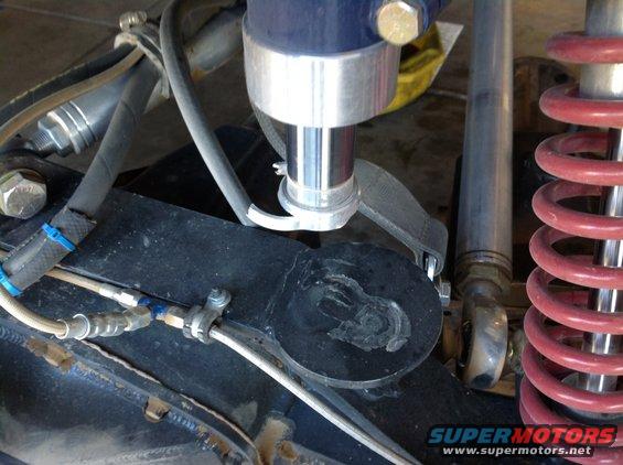 Close-up of suspension parts on an off-road vehicle, showing shock absorber, springs, and hydraulic lines