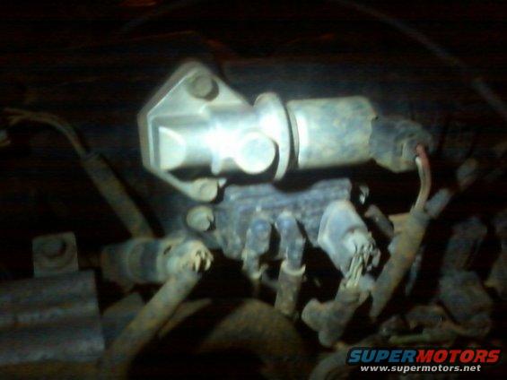 Close-up of an engine part with wires and hoses attached