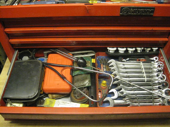 Open red toolbox drawer filled with wrenches, a stethoscope, and other tools