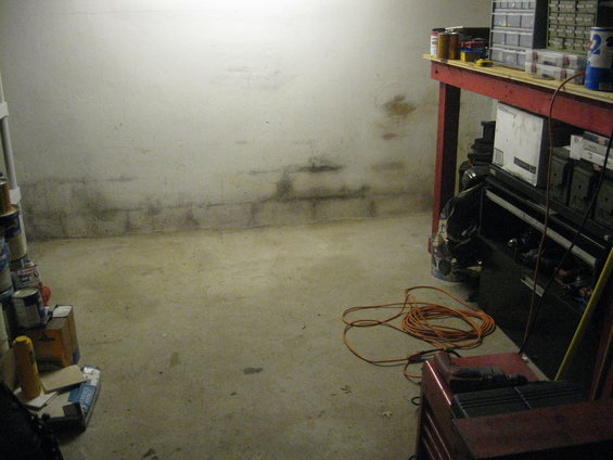 Garage interior with concrete floor, cinder block wall, workbench, and orange extension cord
