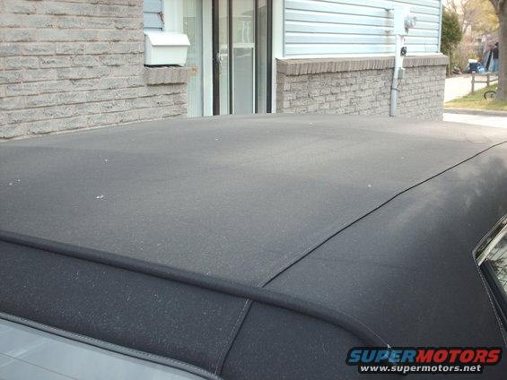 Black fabric car roof with visible stitching and a portion of the rear window