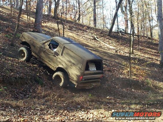 1986 Ford Bronco climbing a muddy, wooded hill