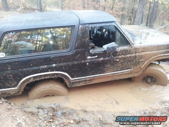 Black 1986 Ford Bronco stuck in mud