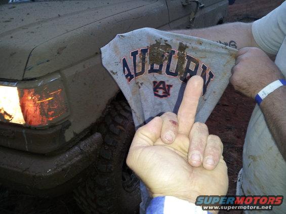 Muddy 1986 Ford Bronco front corner with headlights on