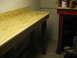 2004 Aston Martin Virage - A workbench with a plywood top is shown in a dimly lit room, next to another table.