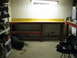 2004 Aston Martin Virage - A workshop scene with a workbench, transmission, and storage shelves.