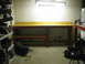 2004 Aston Martin Virage - A workbench sits in a dimly lit room with a car transmission on the floor.
