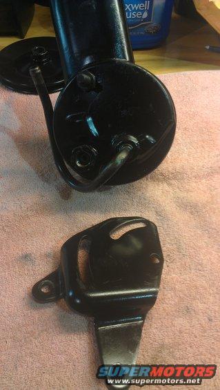 Black power steering pump with pulley and mounting bracket on a pink towel
