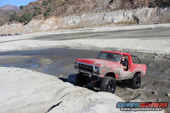 1978 Ford Bronco driving through water, red exterior