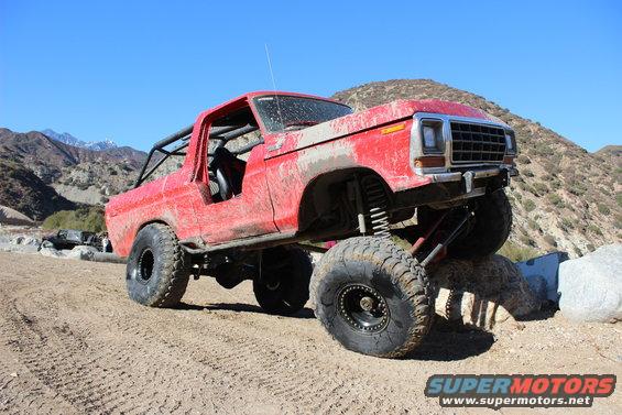 Red 1978 Ford Bronco with off-road modifications on rocky terrain