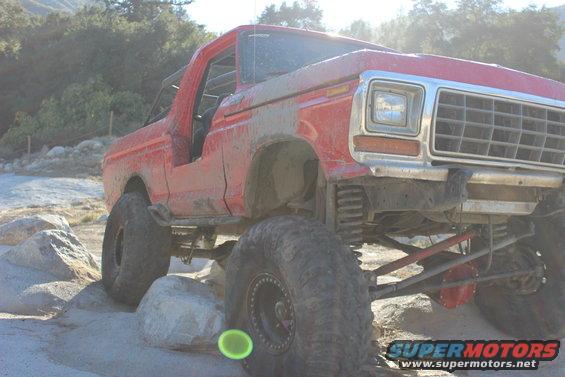 Red 1978 Ford Bronco on rocks, front quarter view, lifted suspension, off-road tires