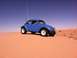 1970 Volkswagen Beetle - A blue 1970 Volkswagen Beetle Baja Bug navigates sandy terrain under a clear blue sky, a flag attached to its antenna.